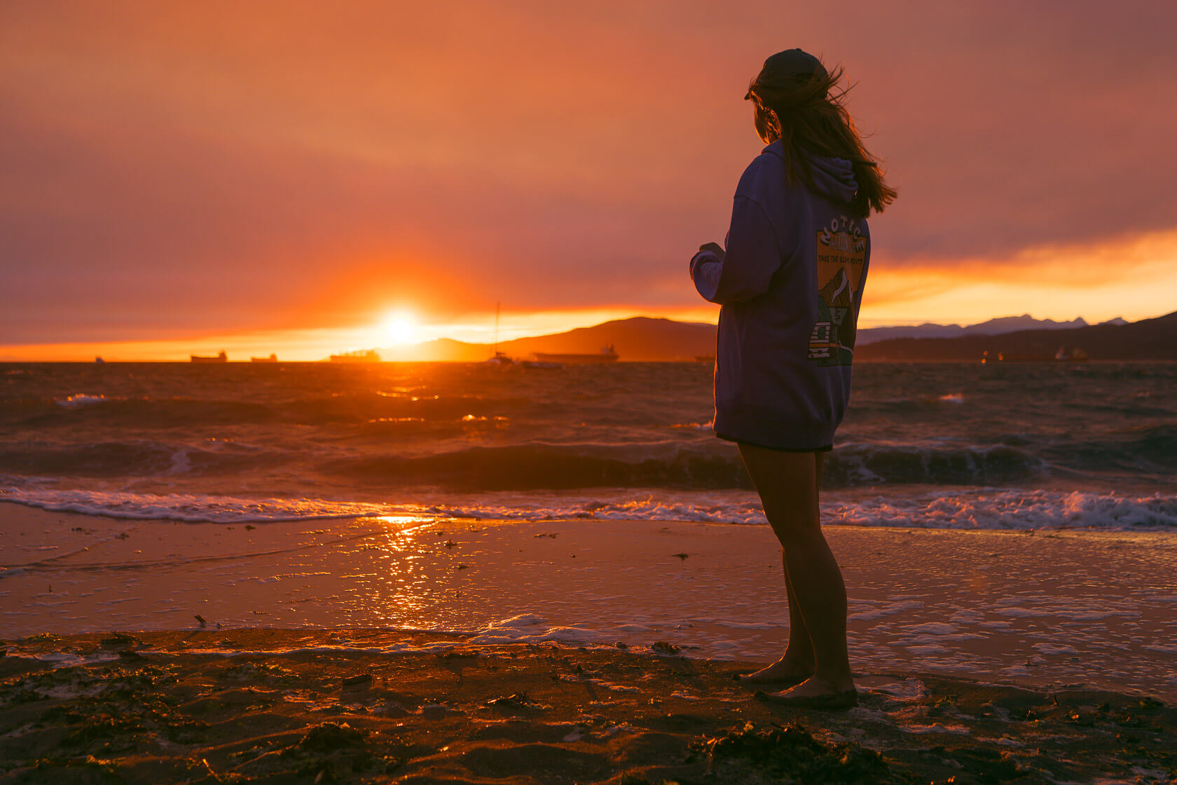 barefoot woman looking towards the setting sun in Vancouver 