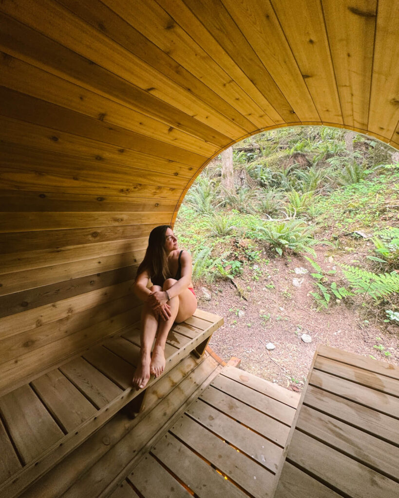 Woman relaxing in a sauna with a forest view window at Moonshine Spa