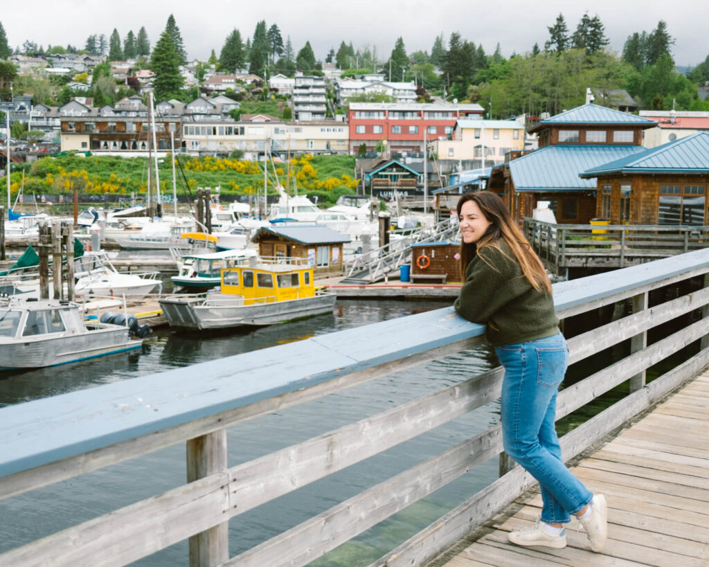 Woman standing on a pier at Gibsons Landing, Sunshine Coast BC, overlooking boats in the harbour