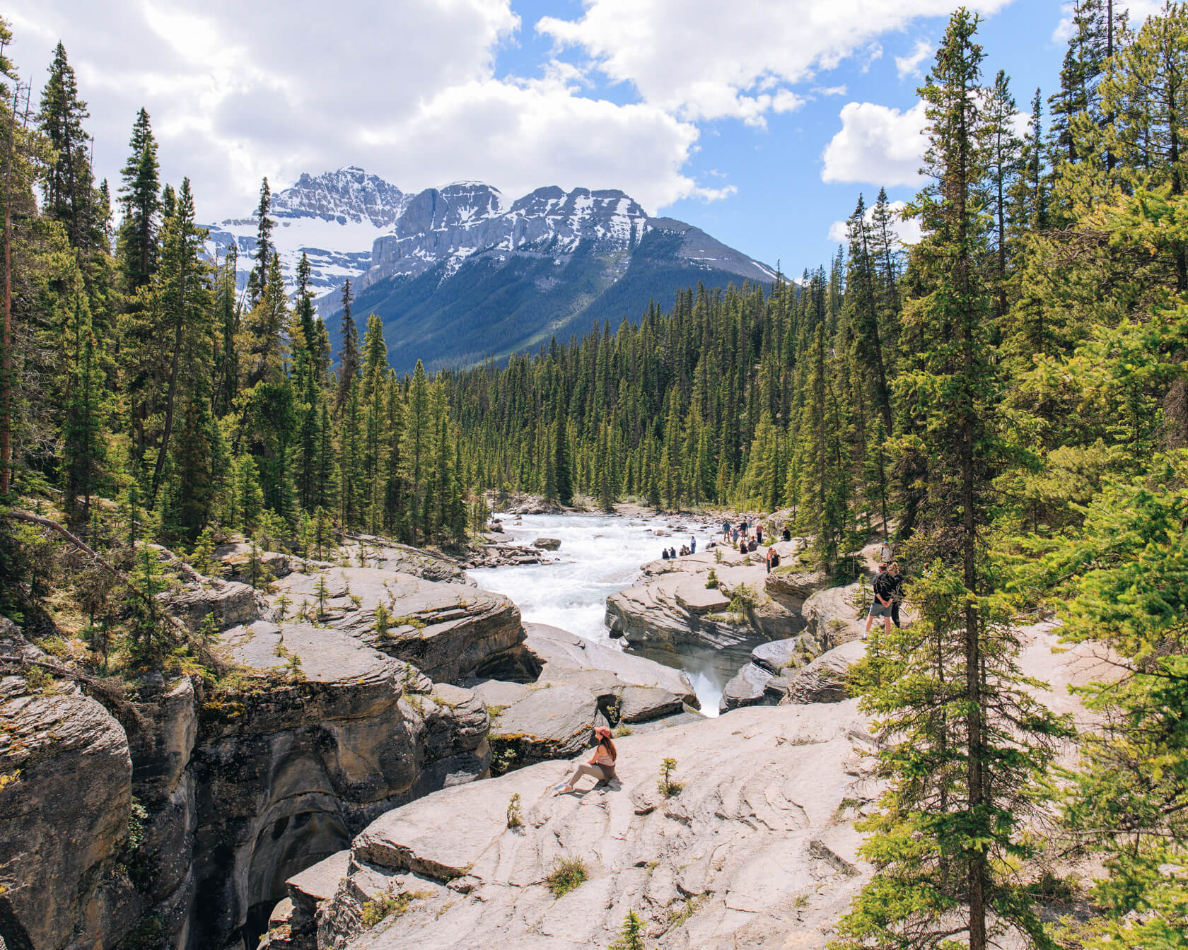 Woman sitting on rock at Mistaya Canyon with Mt Sarbach in the background